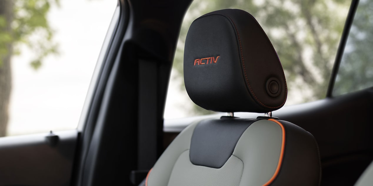 A Close-Up of a Chevy Trax ACTIV Front Seat Featuring Gray Upholstery, Orange Accent Stitching, and an Embroidered ACTIV Headrest Badge.