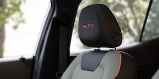 A Close-Up of a Chevy Trax ACTIV Front Seat Featuring Gray Upholstery, Orange Accent Stitching, and an Embroidered ACTIV Headrest Badge.