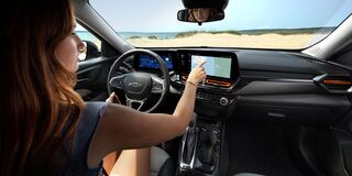 A Driver Interacting With the Chevy Trax Infotainment Touchscreen While Seated Behind the Steering Wheel.