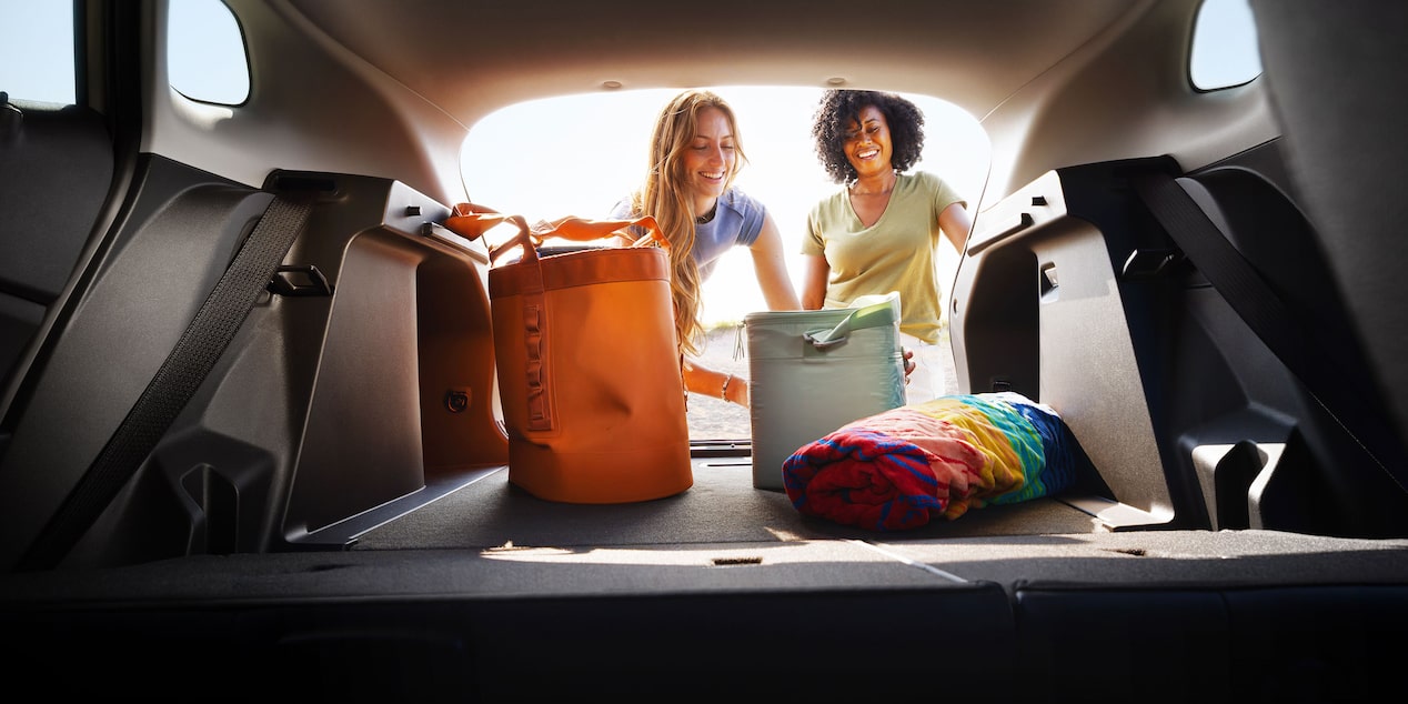 A View From the Chevy Trax Cargo Area Looking Toward Two People Standing Behind the Open Liftgate With Travel Bags and Luggage Inside the Vehicle.