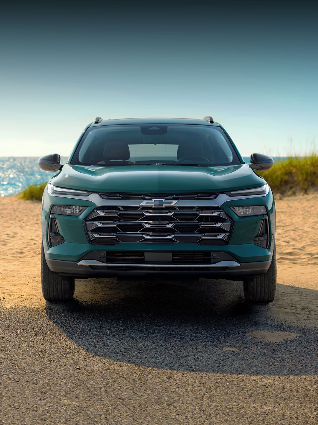 A Chevy Trax ACTIV Parked on a Sandy Beach With Ocean Views in the Background.