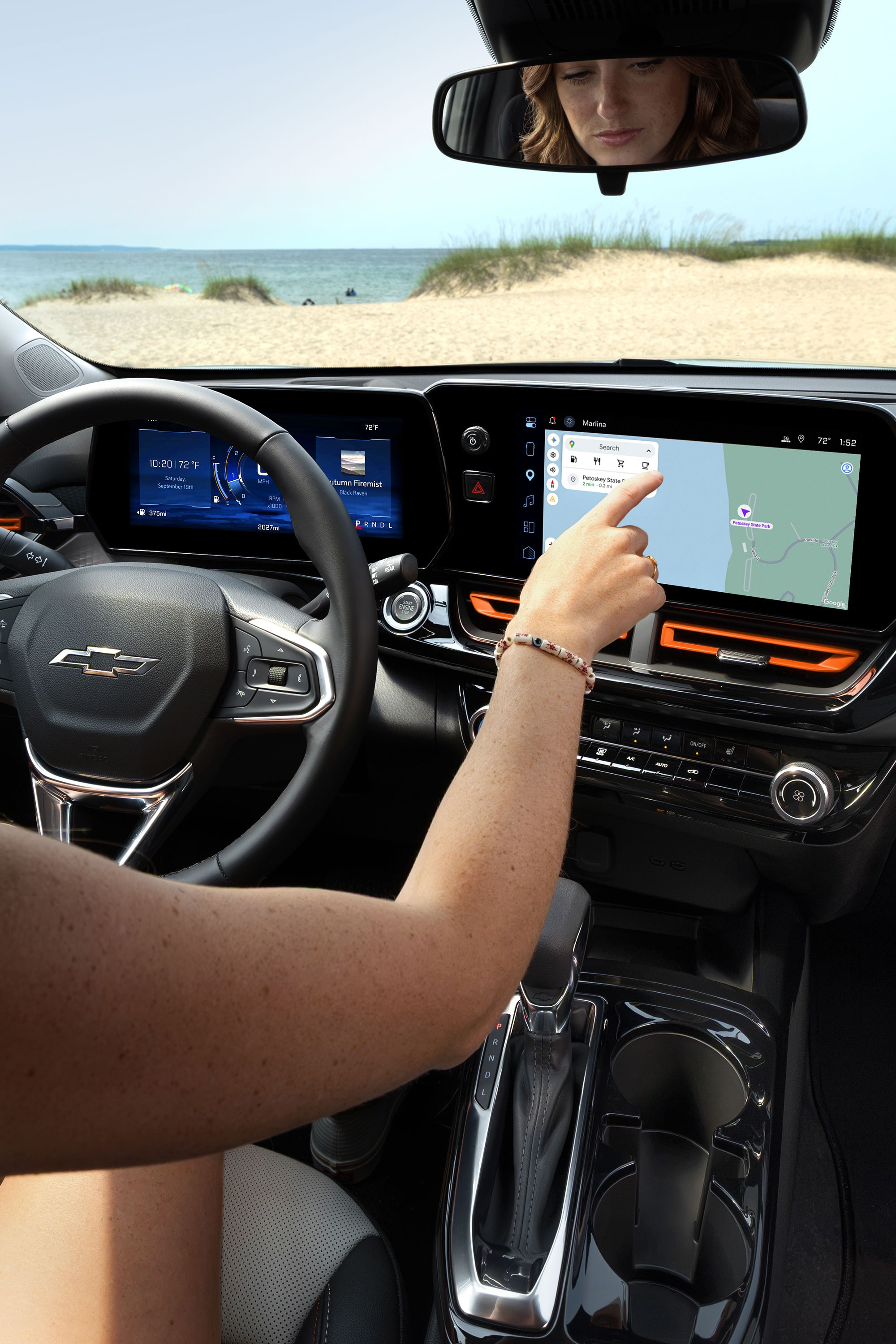 A Driver Interacting With the Chevy Trax Infotainment Touchscreen While Seated Behind the Steering Wheel.