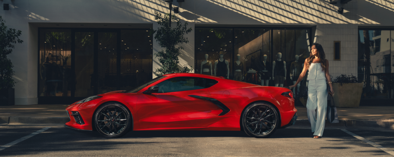Profile View of a Red Chevrolet Corvette Stingray While a Woman Walks Behind the Rear End