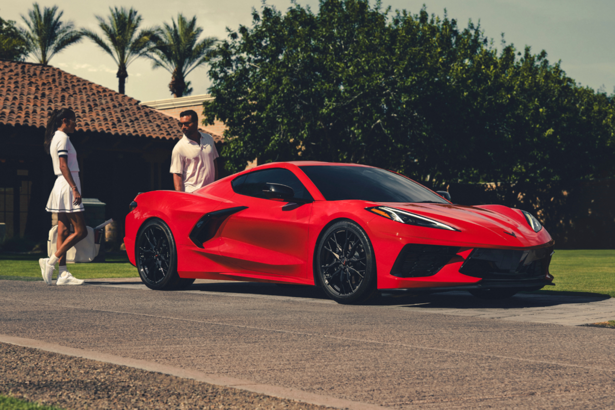 People Standing Next To Red Corvette Stingray