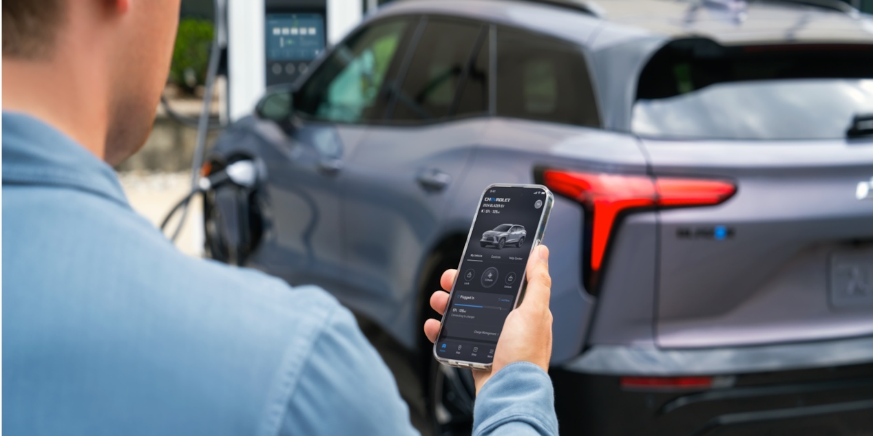 Man Using Smartphone While Charging his Blazer EV