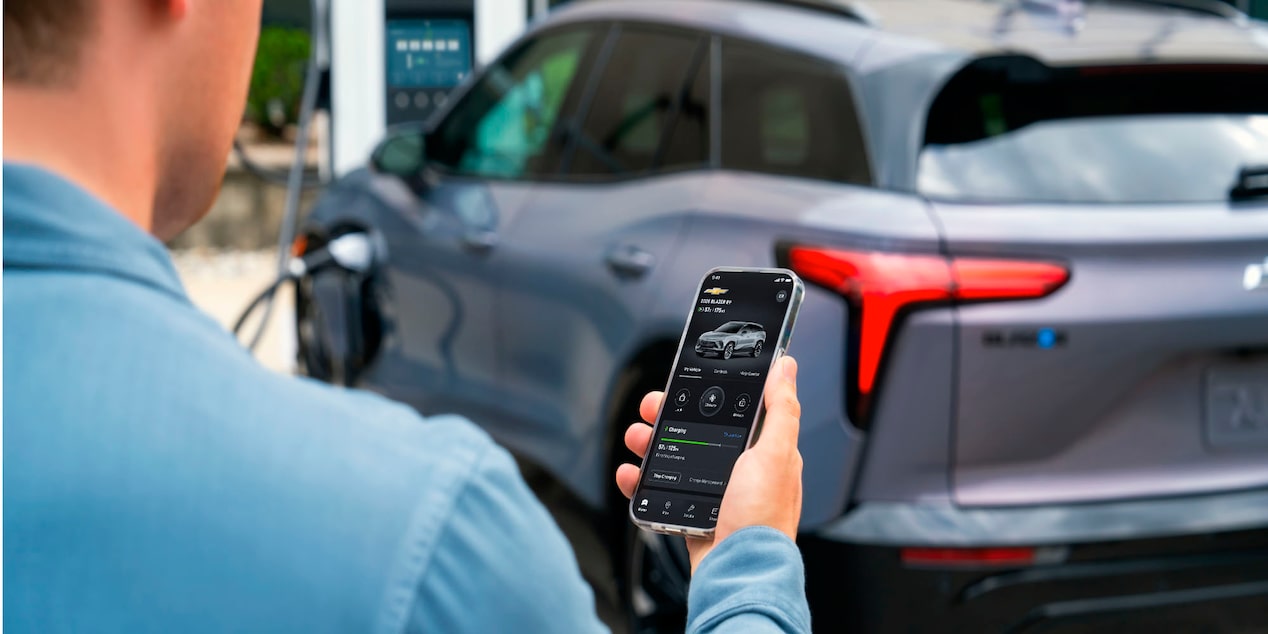 Man Using Smartphone While Charging his Blazer EV