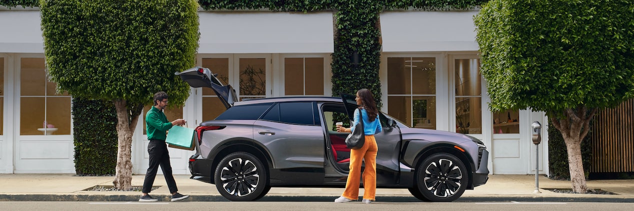Couple Loading Items into Blazer EV Parked on City Street