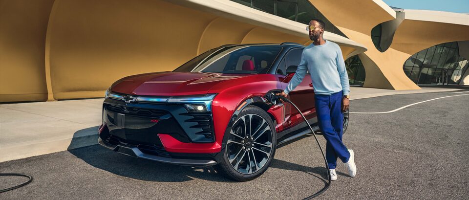 Man Charging His Chevy Blazer EV In Front Of Modern Building