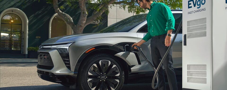 Una persona enchufa una Blazer EV color plata para una carga