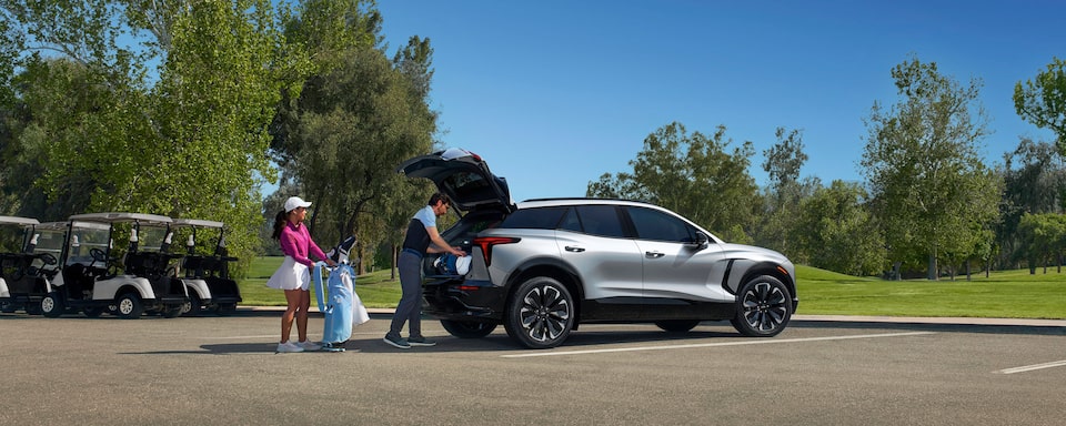 People Loading Golf Clubs into Silver Blazer EV Parked at Golf Course