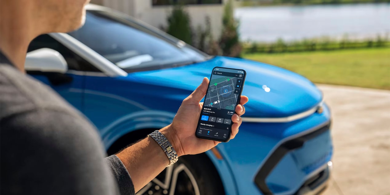 Un hombre usando la aplicación myChevrolet en un iPhone, con una Equinox EV en Azul de fondo