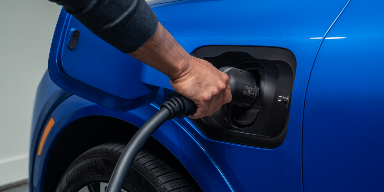 A Man Plugging in Charger to  2024 Equinox EV Port