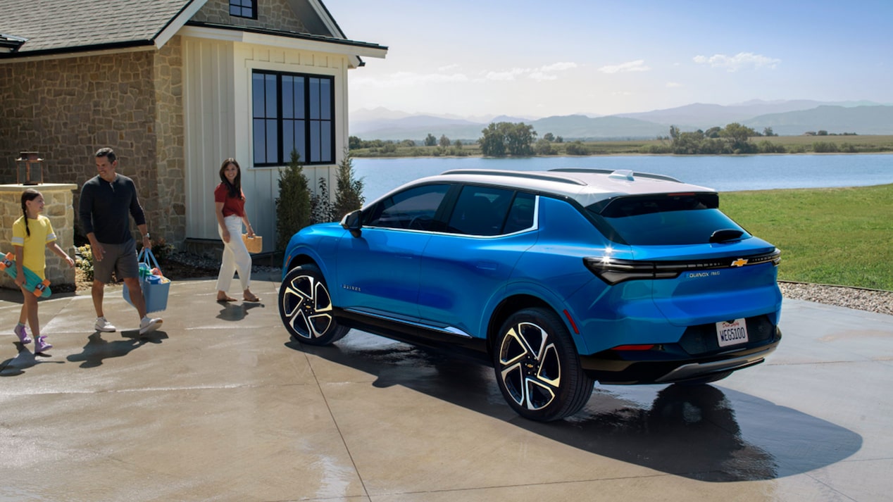 Una familia llevando bolsas de compras a su Equinox EV estacionado.