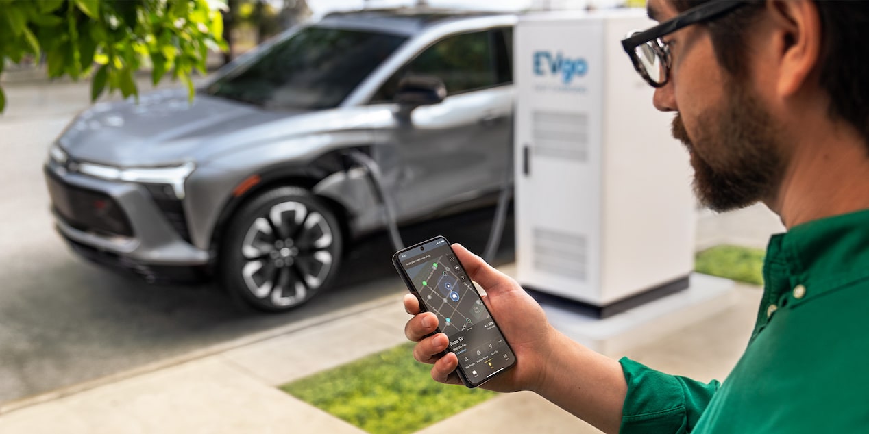 Un hombre utiliza su aplicación MyChevrolet para encontrar una estación de carga pública para vehículos eléctricos