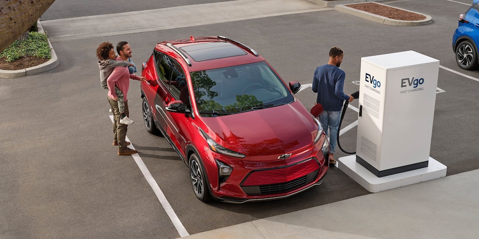 Una familia cargan su Chevy Bolt EUV en una estación de carga pública