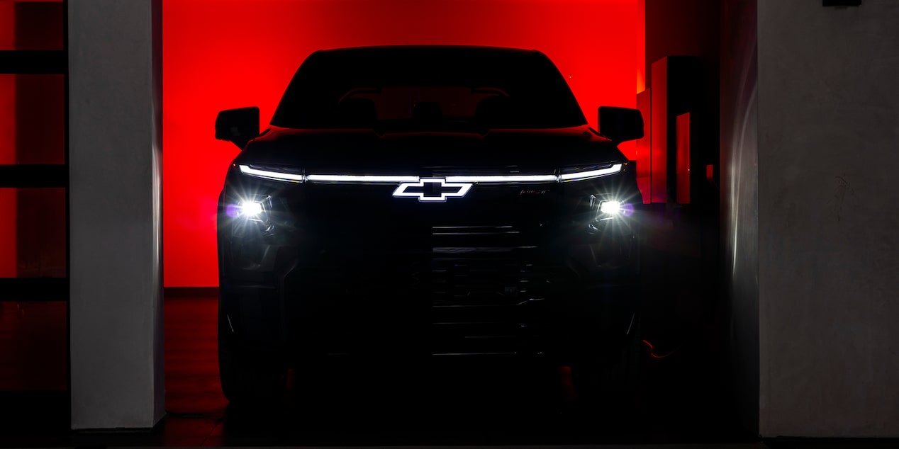 Chevy Silverado EV Parked in a Dark Garage with Headlights and Logo Illuminated