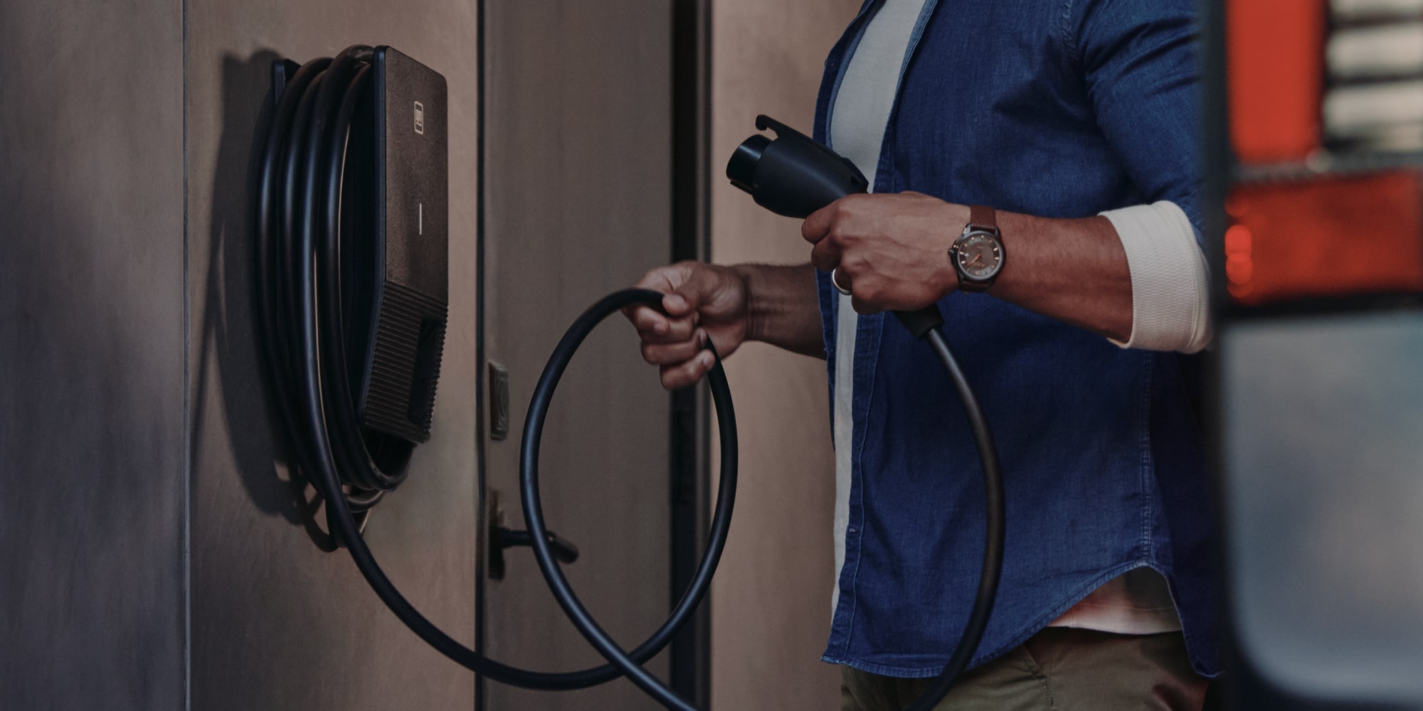 Close-up of a Man Holding onto an EV Home Charger Cord in a Garage