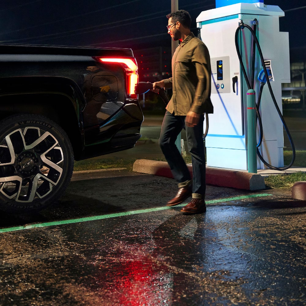 Man Standing Next to Charging Silverado EV