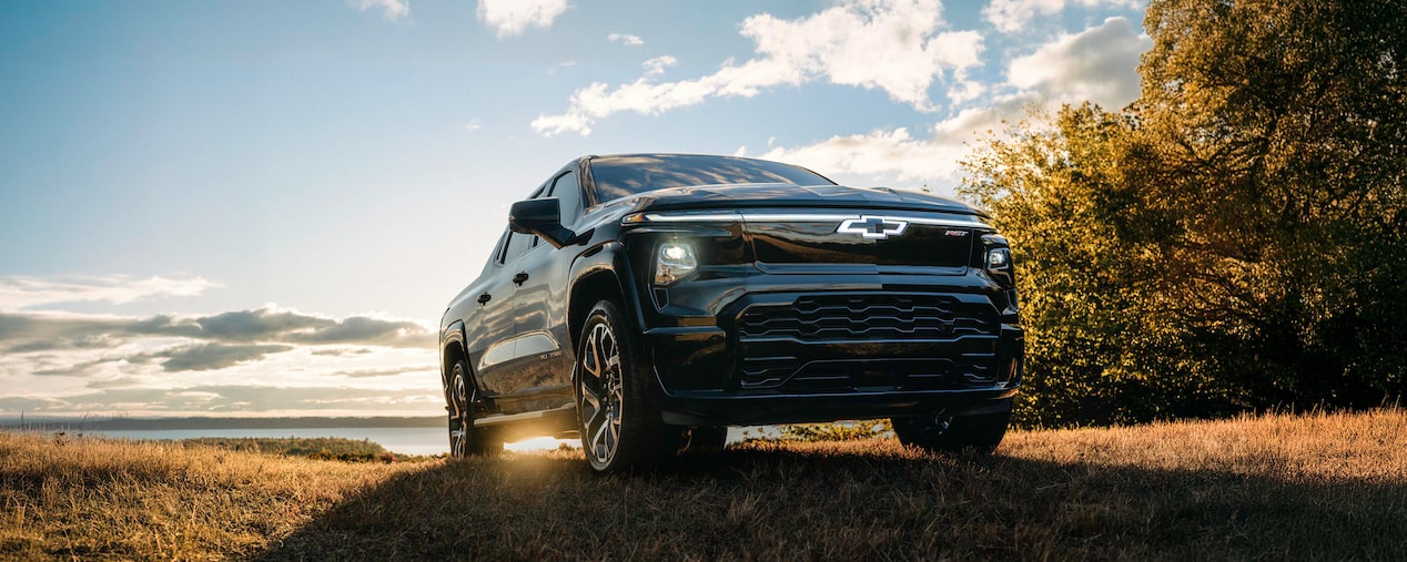 Black Silverado EV Park on Grass With A Sunset
