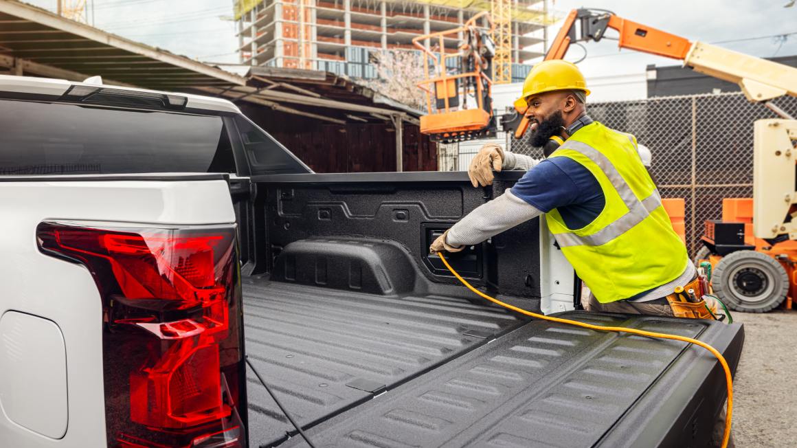Un trabajador de la construcción enchufando un cable de extensión en la caja de una Silverado EV