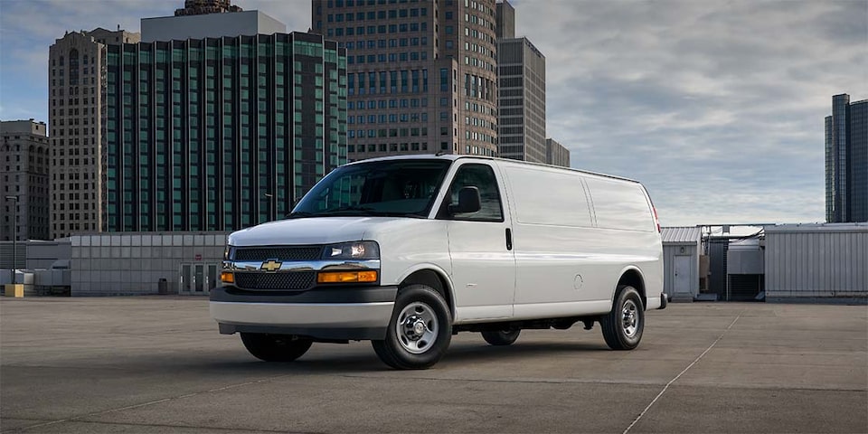 2023 Chevy Express Cargo Van Parked with a City Backdrop on a Cloudy Day