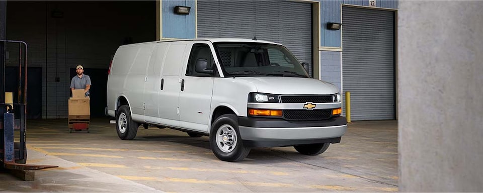 A Man Approaches the 2023 Chevy Express Cargo Van Outside of a Warehouse