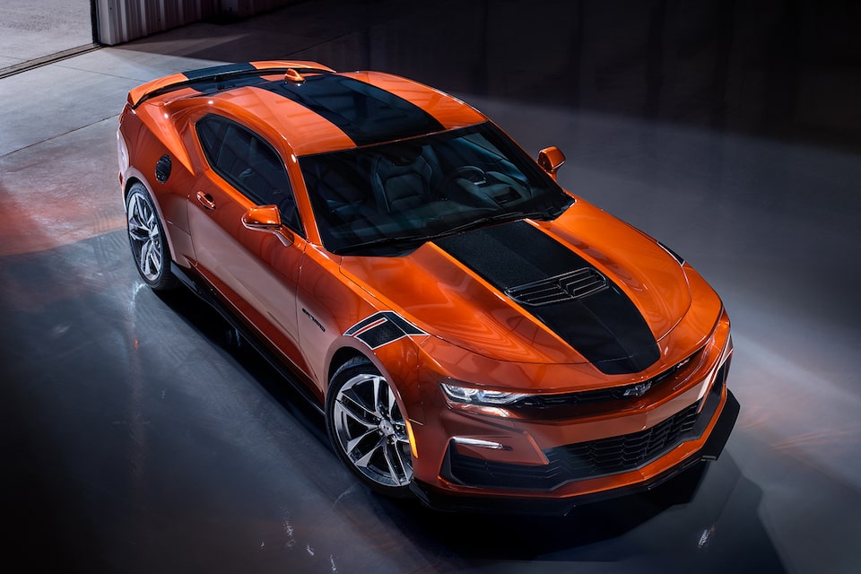 Orange Camaro with black racing stripe sits in the sunlight