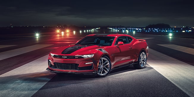 Red Camaro with a Black Racing Stripe Parked on an Open Road at Night