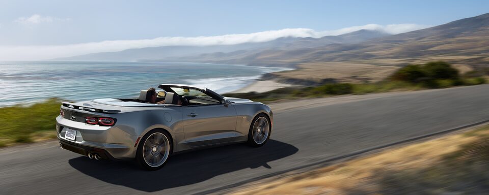 Grey Camaro convertible driving near the shore