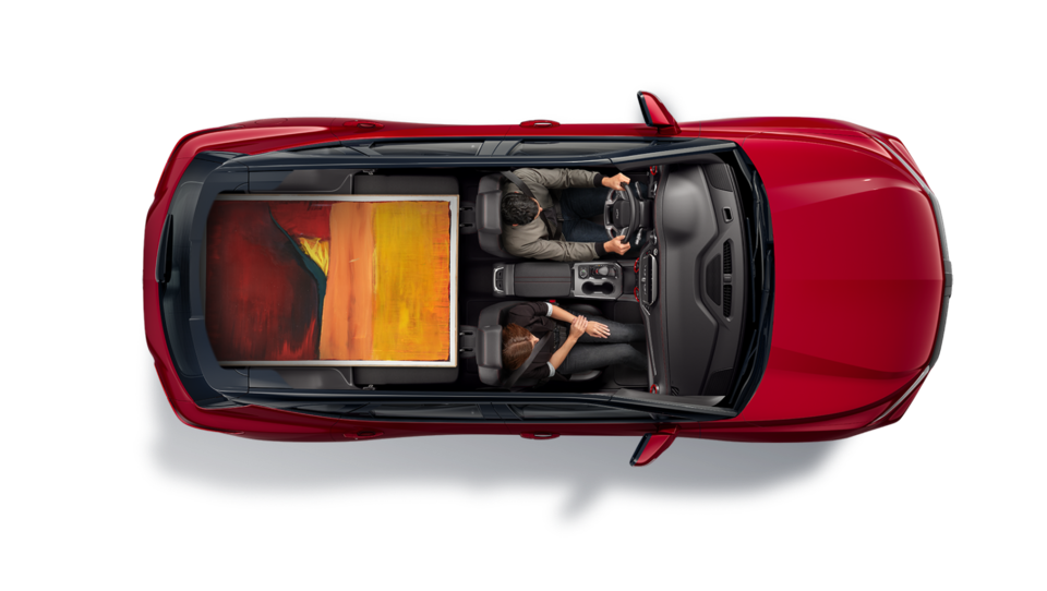 An Aerial Cut-Out View of the Blazer with a Couple Sitting in the Driver & Passenger Seat While Hauling a Large Painting