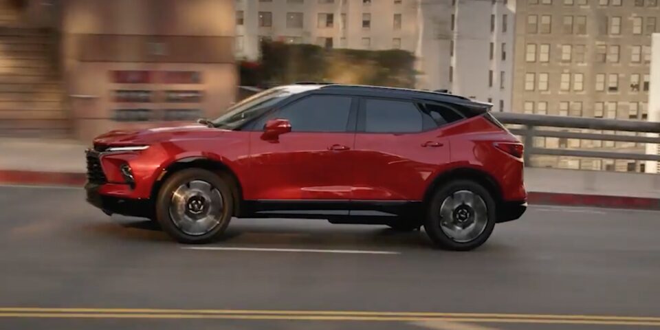 Red Chevy Blazer Driving on an Open City Roadway During the Day