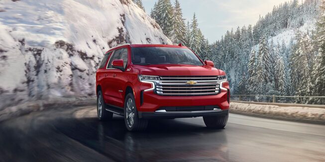 Una Chevy Suburban 2023 en Rojo Radiante Tintcoat circulando por un camino de montaña cubierto de hielo