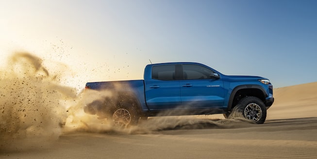 The 2023 Bright Blue Metallic Chevy Colorado Easily Driving on Uneven, Sandy Terrain