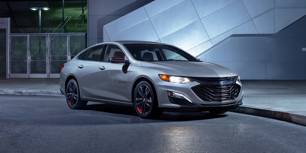 The 2024 Chevy Malibu Redline Edition Parked In Front Of A Building At Night