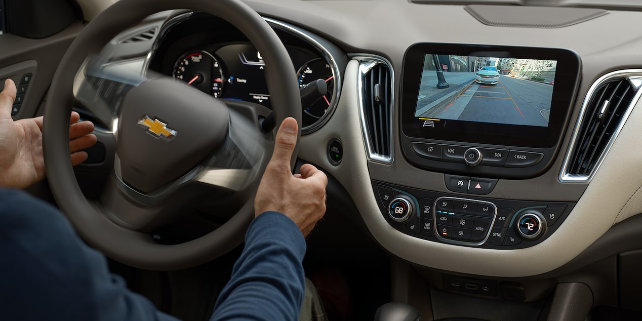 Driver Utilizing The Automatic Parking Assist Feature Inside The 2024 Chevy Malibu