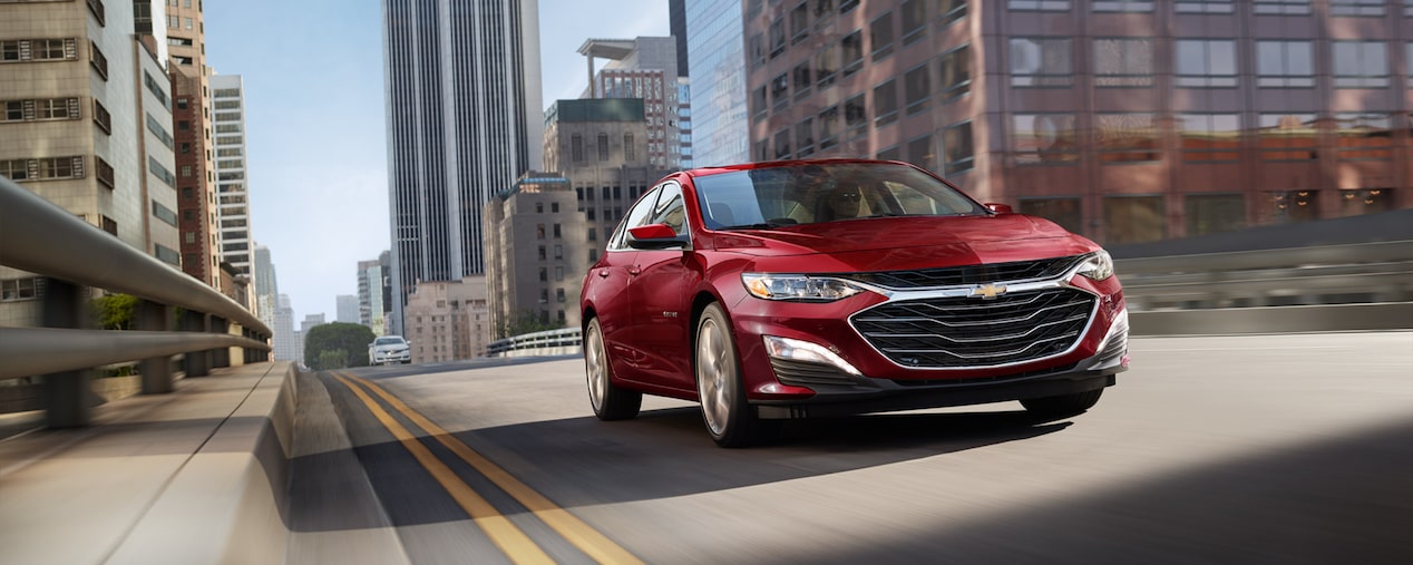 2024 Chevy Malibu in Radiant Red Tintcoat Driving Through A City