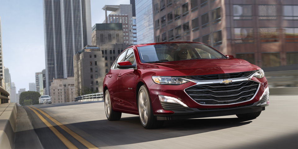 2024 Chevy Malibu in Radiant Red Tintcoat Driving Through A City