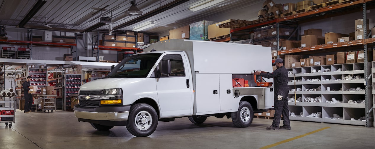 Vans comerciales Express 2024 de Chevy estacionadas fuera del edificio de oficinas de vidrio