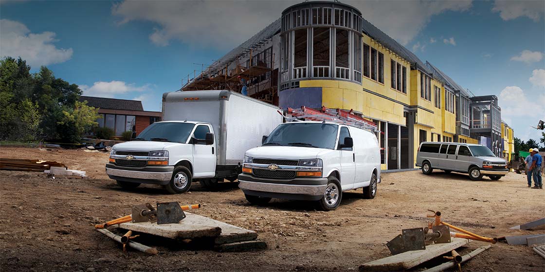 Varios vehículos comerciales Chevy estacionados en un lugar de construcción