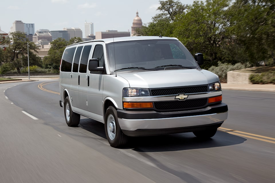 2024 Chevy Commercial Express Passenger Van Driving Down City Road