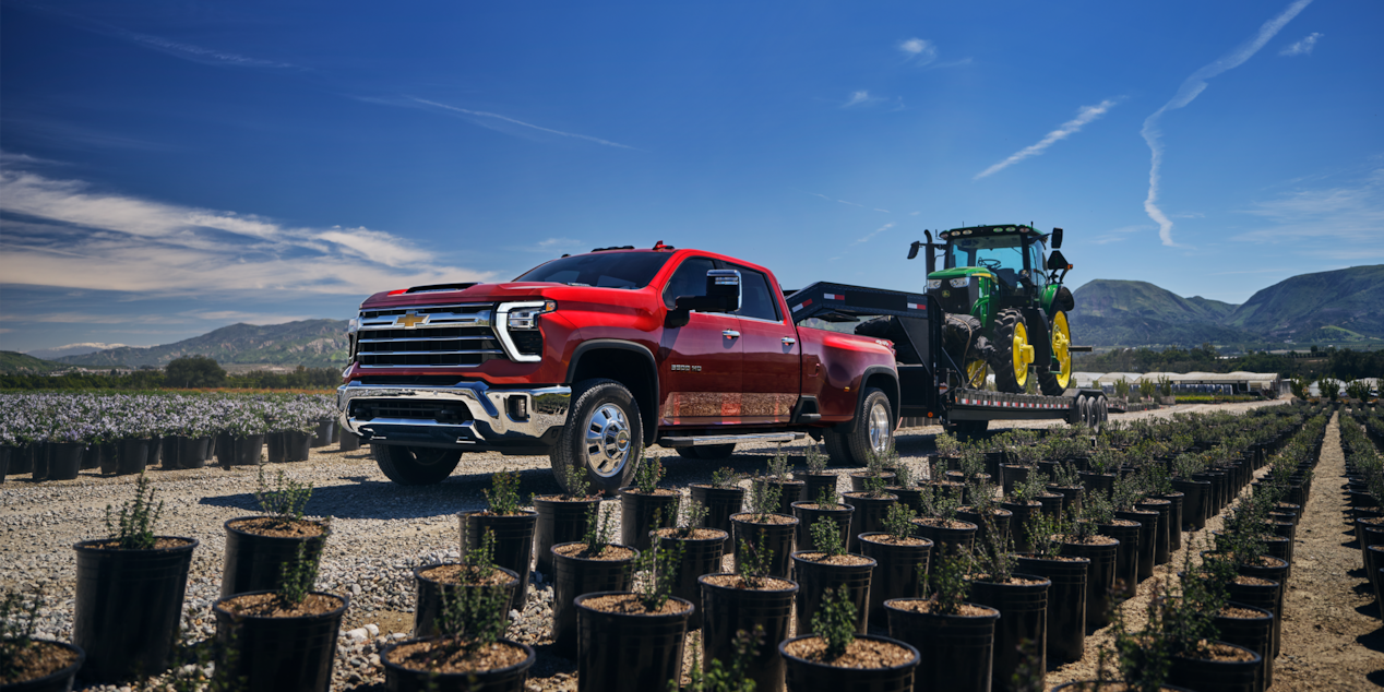 Red Silverado HD Towing Agricultural Equipment on Worksite