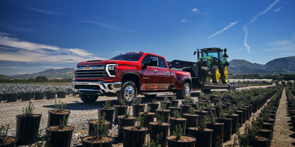 Red Silverado HD Towing Agricultural Equipment on Worksite
