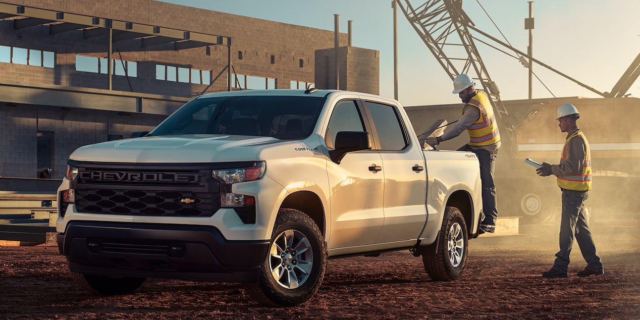 Dos trabajadores de la construcción de pie cerca de una camioneta Chevrolet Silverado 2024
