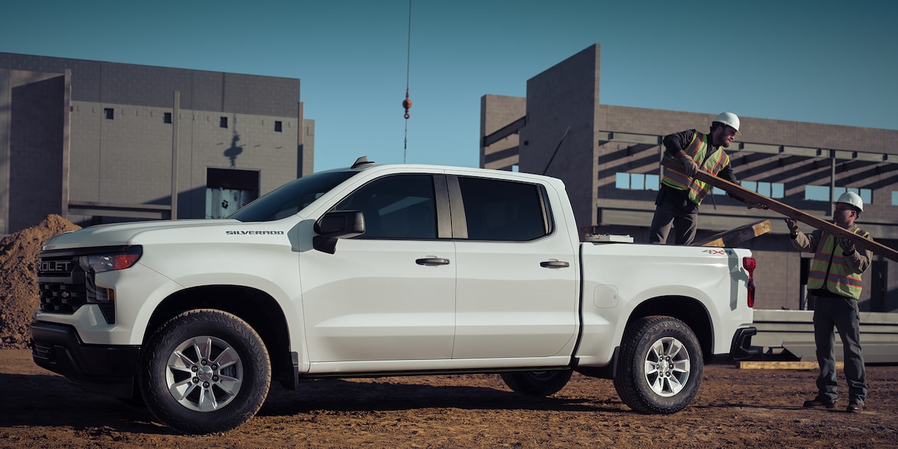 Dos obreros de la construcción descargan materiales de una camioneta Chevrolet Silverado 2024