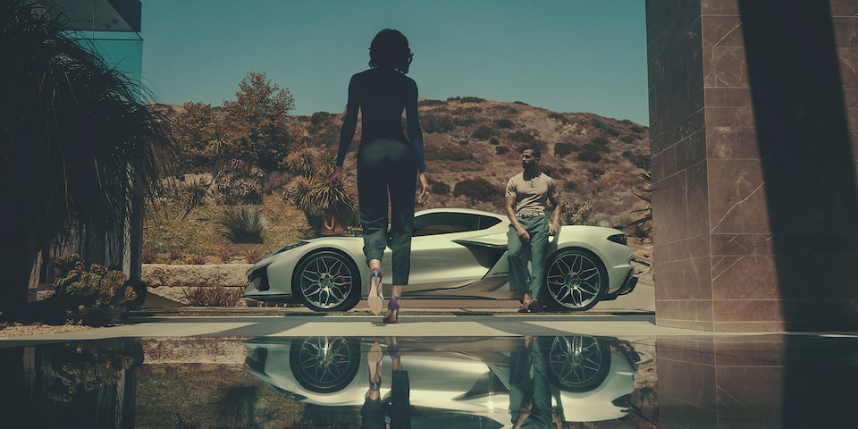 A Man Leans Against His Corvette Z06 as His Wife Approaches with a Mountain Backdrop
