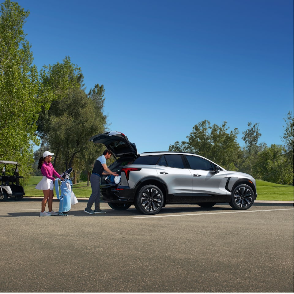 Couple Loading Golf Clubs into Silver Blazer EV Parked at Golf Course