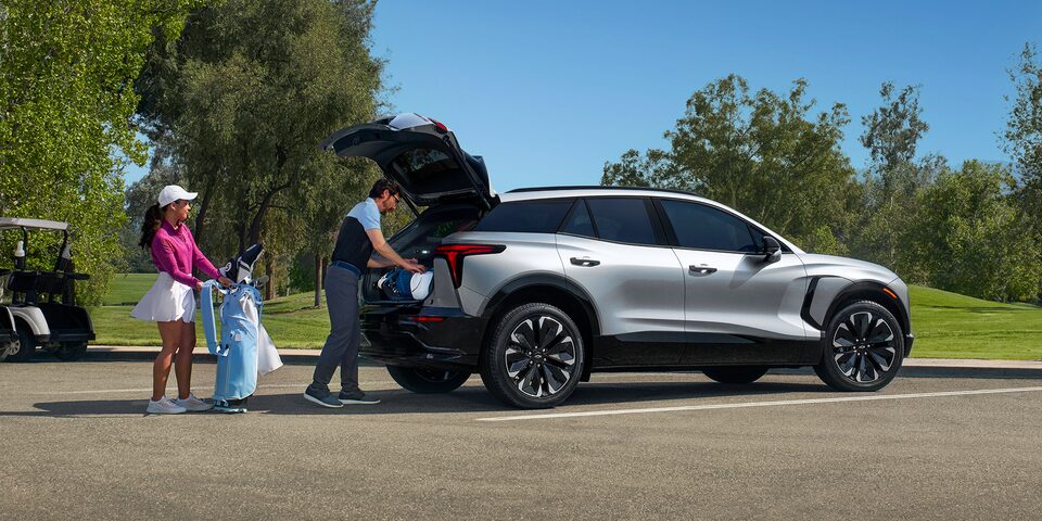 Couple Loading Golf Clubs into Silver Blazer EV Parked at Golf Course
