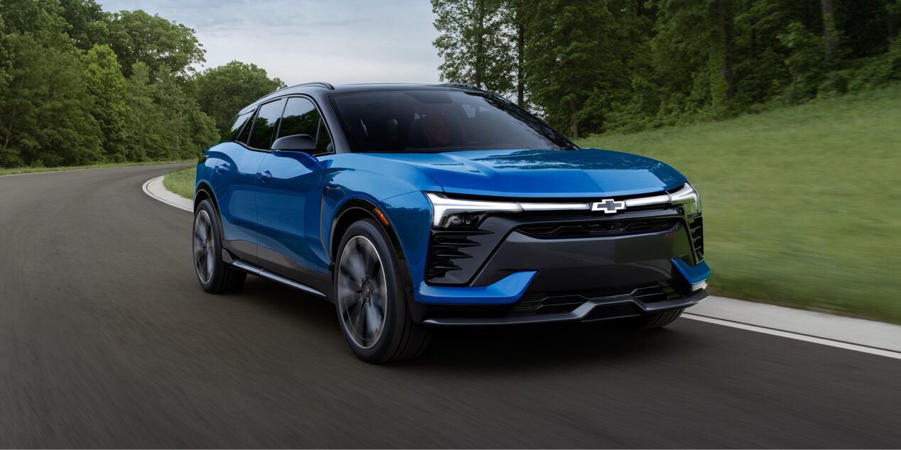 a blue suv driving on a paved road around trees