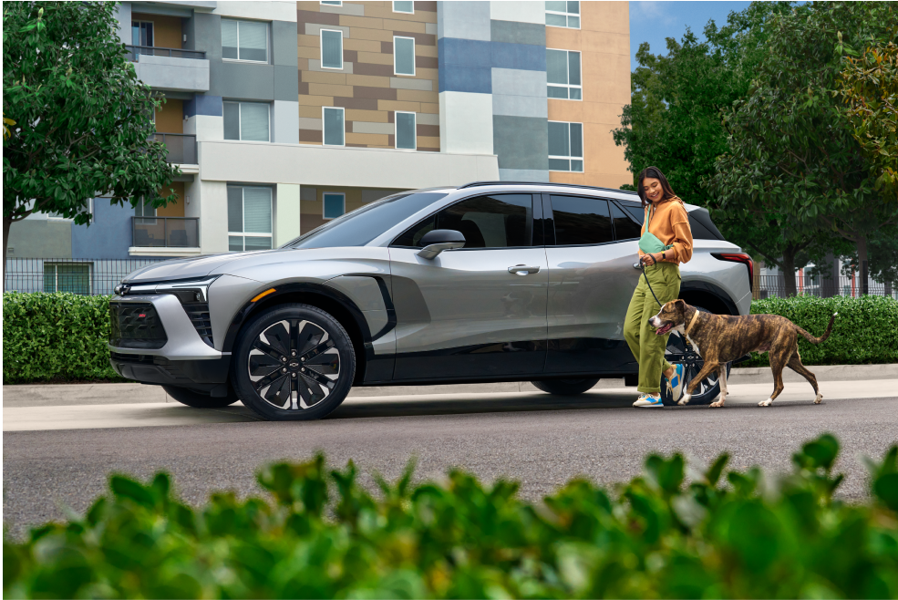 Woman Walking Dog Past Blazer EV Plarked on Street