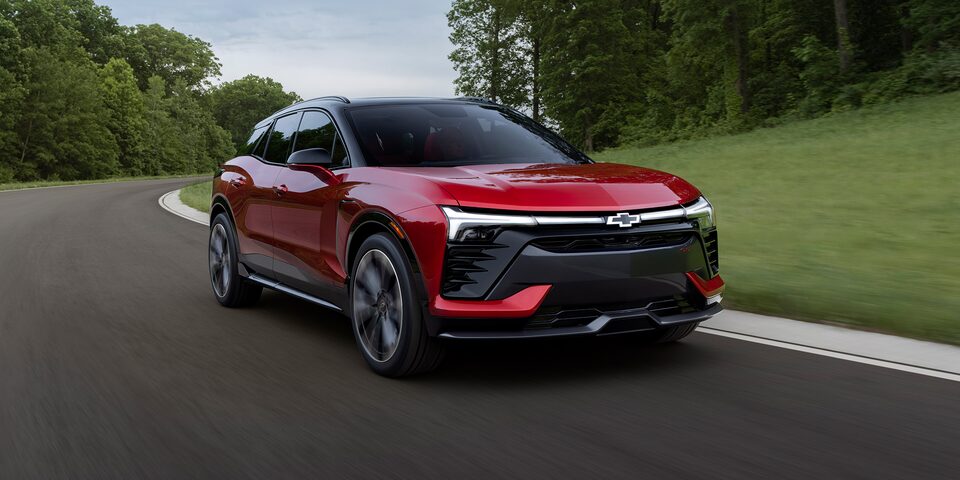 Radiant Red Chevy Blazer EV Driving Through a Curved Forest Road